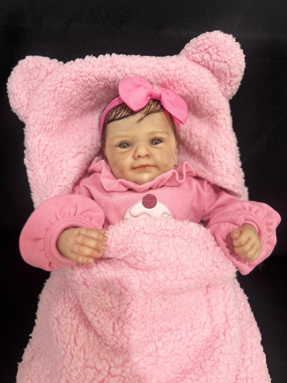 Bebê reborn em vinil com roupinha rosa e laço, finalizada à mão